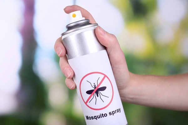 Hand holding mosquito spray on nature background